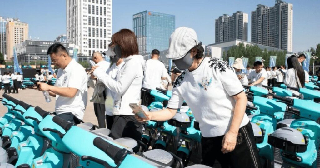 Người dùng mở khóa xe hai bánh màu xanh bằng mã QR trên ghi-đông