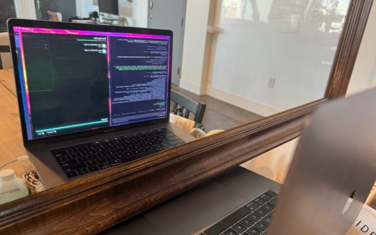 MacBook cũ đặt trước gương để webcam quan sát màn hình