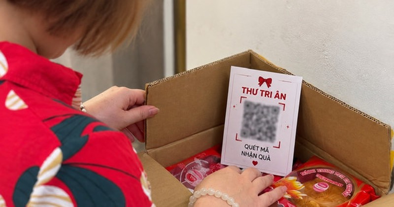 Màn hình điện thoại hiển thị mã QR trên một bưu phẩm quà tặng