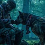 Brad Pitt trong vai James đứng cạnh chú chó quân vụ Odin giữa vùng hoang dã